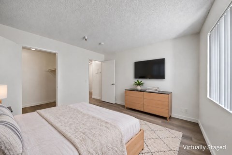 A bedroom with a bed, dresser, and television.