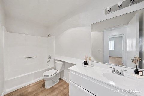 A white bathroom with a toilet, sink, and mirror.