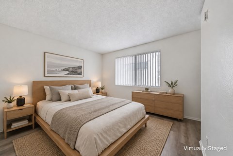 A bedroom with a large bed, a nightstand, and a framed picture on the wall.