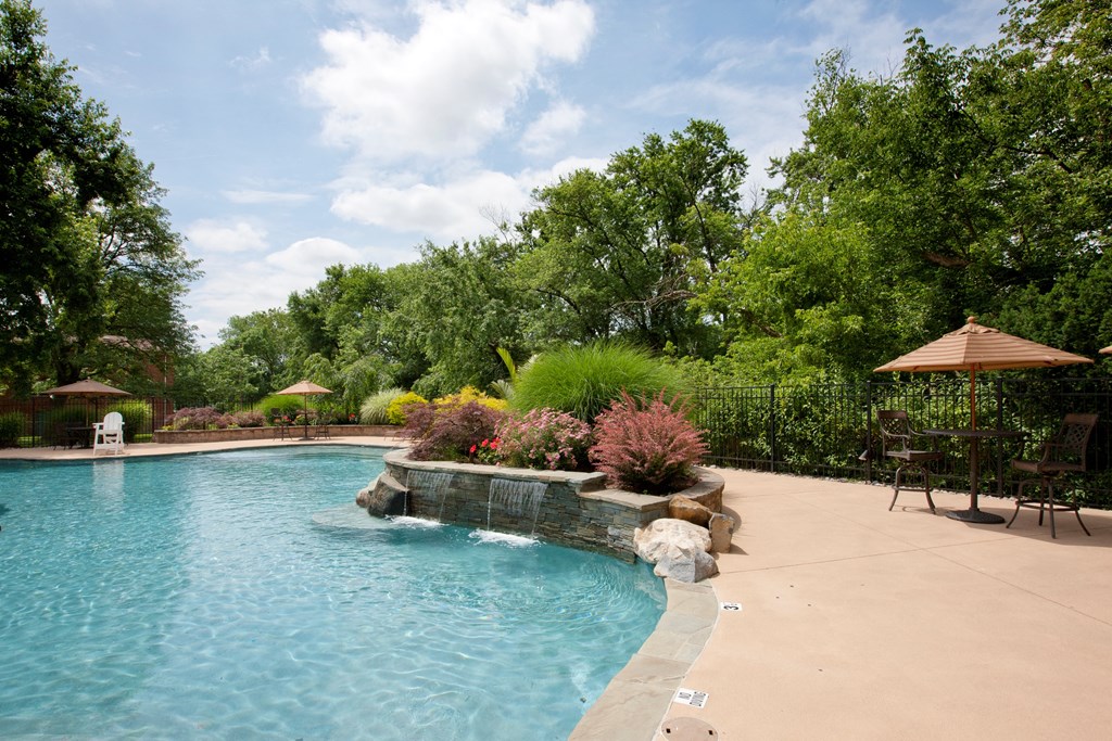A pool surrounded by a garden and trees. at Rivercrest Apartments, Piscataway , NJ