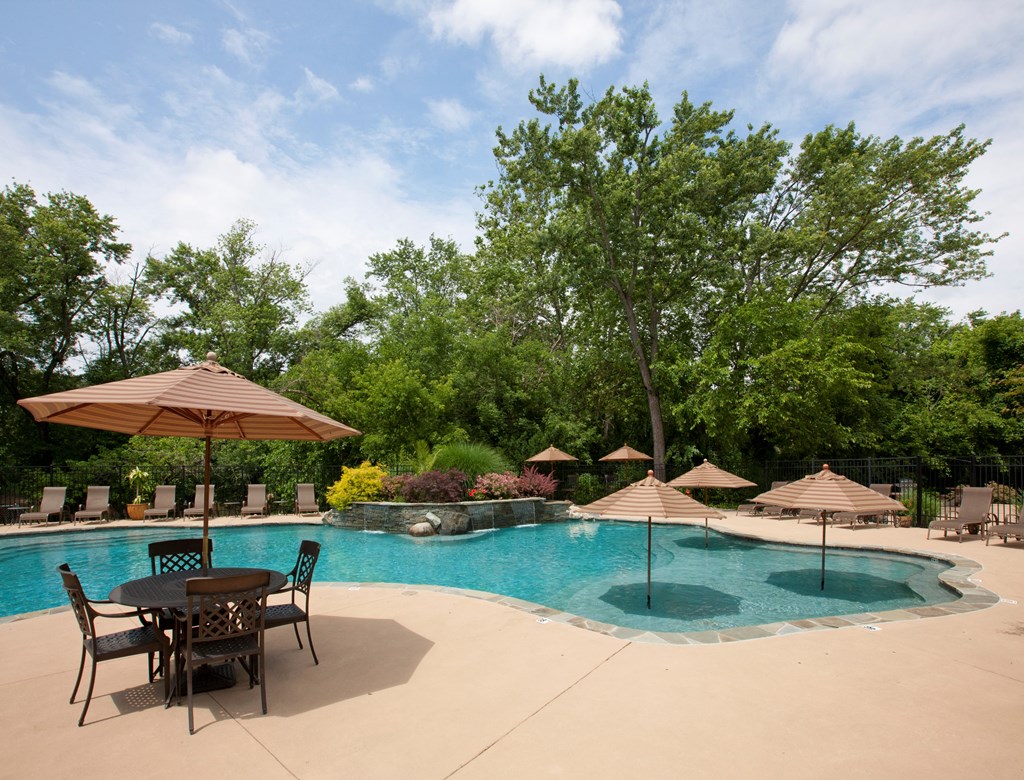 A pool with a table and chairs and umbrellas at Rivercrest Apartments, New Jersey