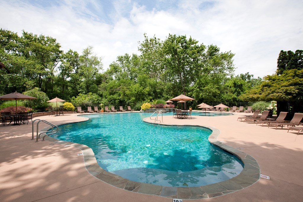A large outdoor swimming pool surrounded by trees and lounge chairs. at Rivercrest Apartments, Piscataway , New Jersey