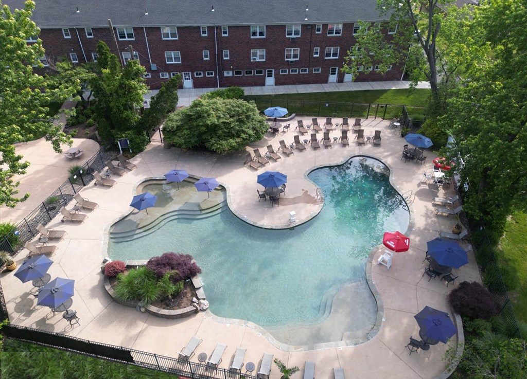 A large outdoor swimming pool surrounded by chairs and umbrellas at Rivercrest Apartments, Piscataway , NJ, 08854