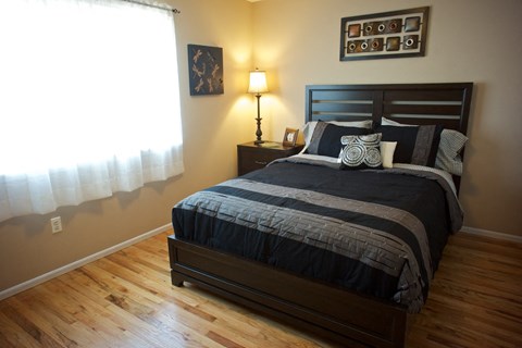 A bedroom with a bed, nightstand, and lamp.