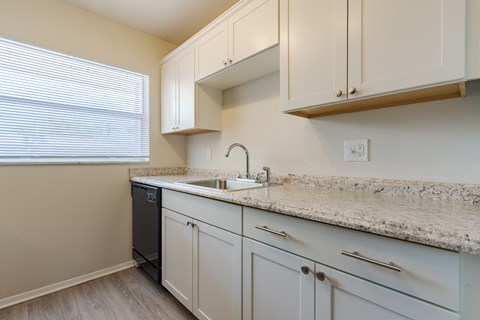 A kitchen with white cabinets and a granite countertop.