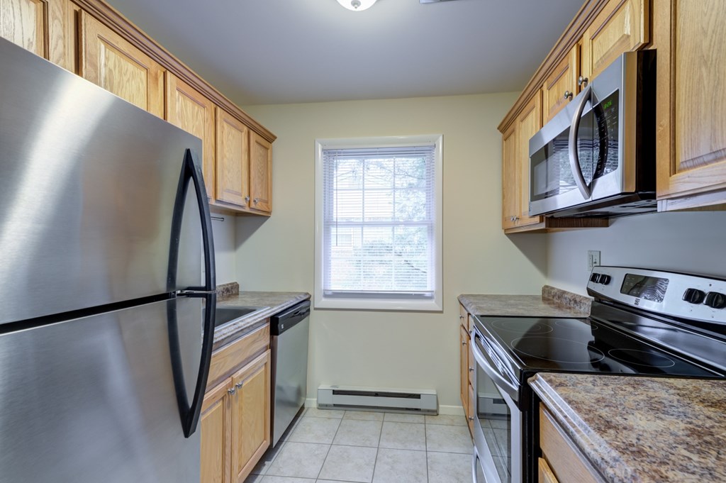A kitchen with a stainless steel refrigerator and wooden cabinets at Rivercrest Apartments, New Jersey