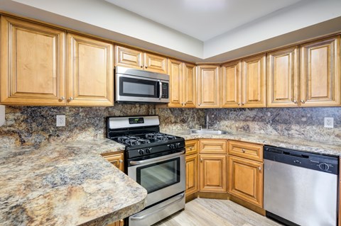 A kitchen with wooden cabinets and granite countertops.