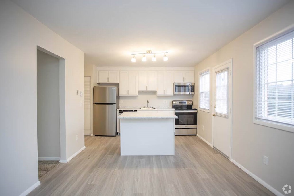 A kitchen with a white island and stainless steel appliances at Kings Gate West Apartments, Camillus