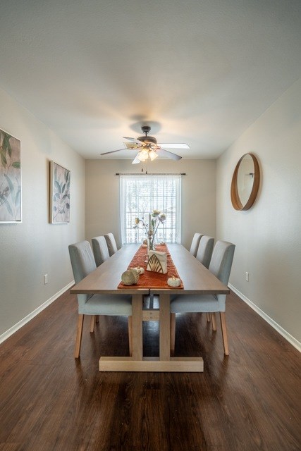 A long wooden dining table with chairs and a fan on the ceiling.