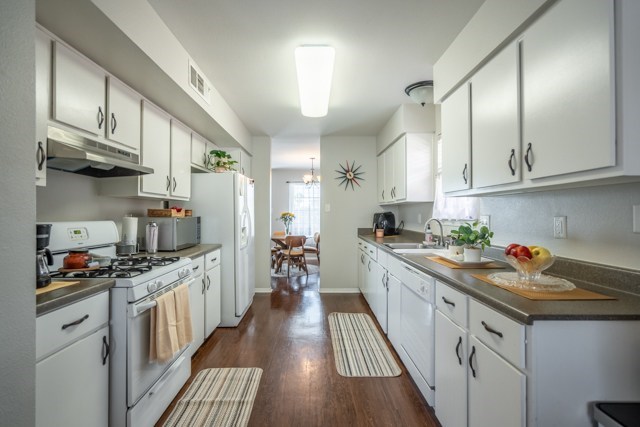 A kitchen with white cabinets and a wooden floor.