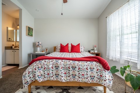 A bedroom with a large bed and a red pillow.