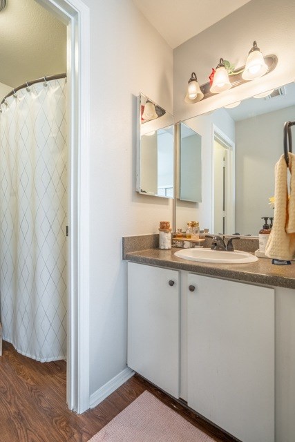 A bathroom with a sink, mirror, and shower curtain.