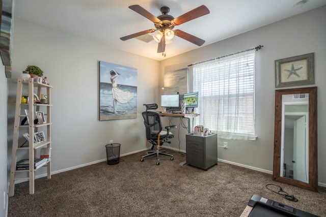 A room with a ceiling fan and a painting of a woman on the wall.
