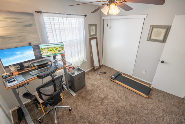 A room with a desk, chair, and a treadmill.