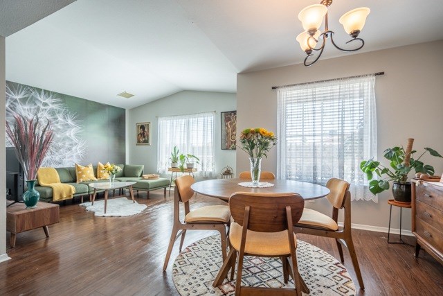 A living room with a green couch, a wooden table and chairs, and a painting on the wall.