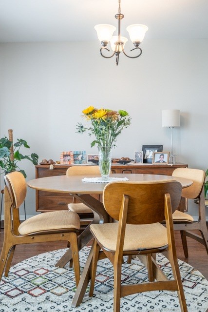 A dining room with a table, chairs, and a vase of flowers.