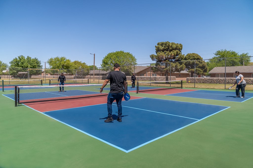a group of people playing tennis on a tennis court  at The Village at Cottonwood Springs, Texas, 79934