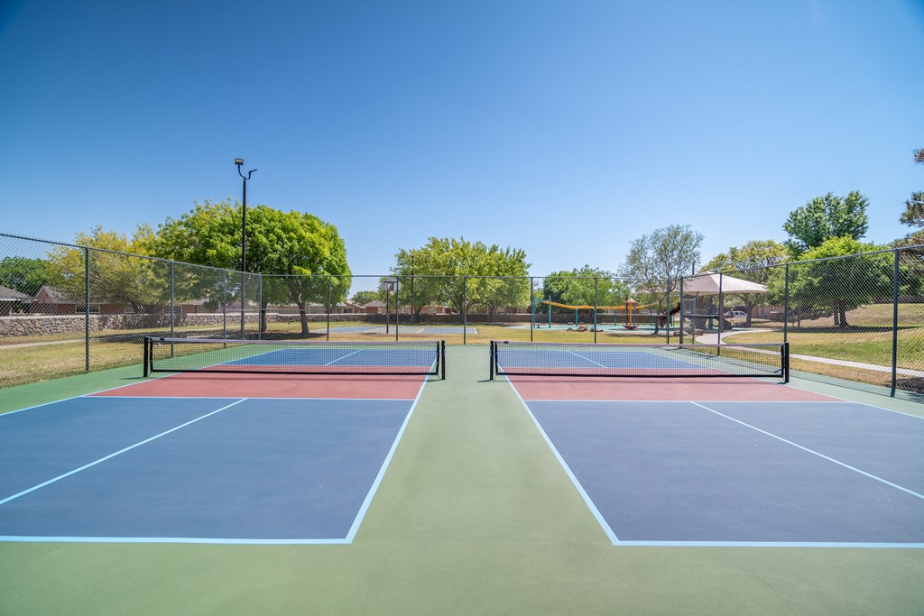a tennis court with four tennis courts on it on a sunny day  at The Village at Cottonwood Springs, El Paso, TX, 79934