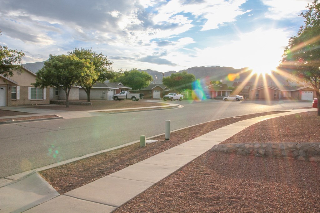 a street with houses and trees and the sunset  at Village of Cottonwood Springs in El Paso, TX