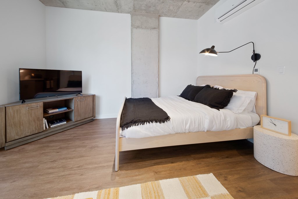 A bedroom with a bed, a TV, and a wooden cabinet.
