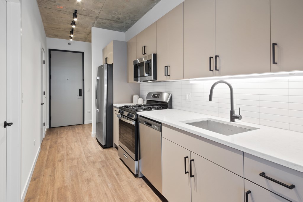 A kitchen with a sink, stove, and refrigerator.