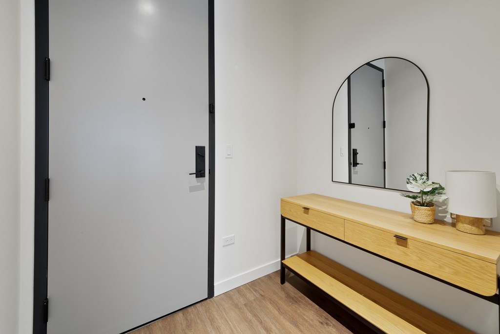 A white door with a black handle and a mirror above a wooden bench.