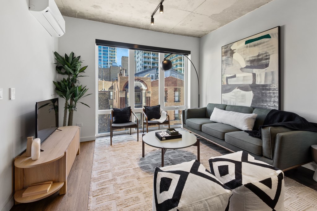 A living room with a grey couch, a wooden cabinet, a coffee table, and a large window.