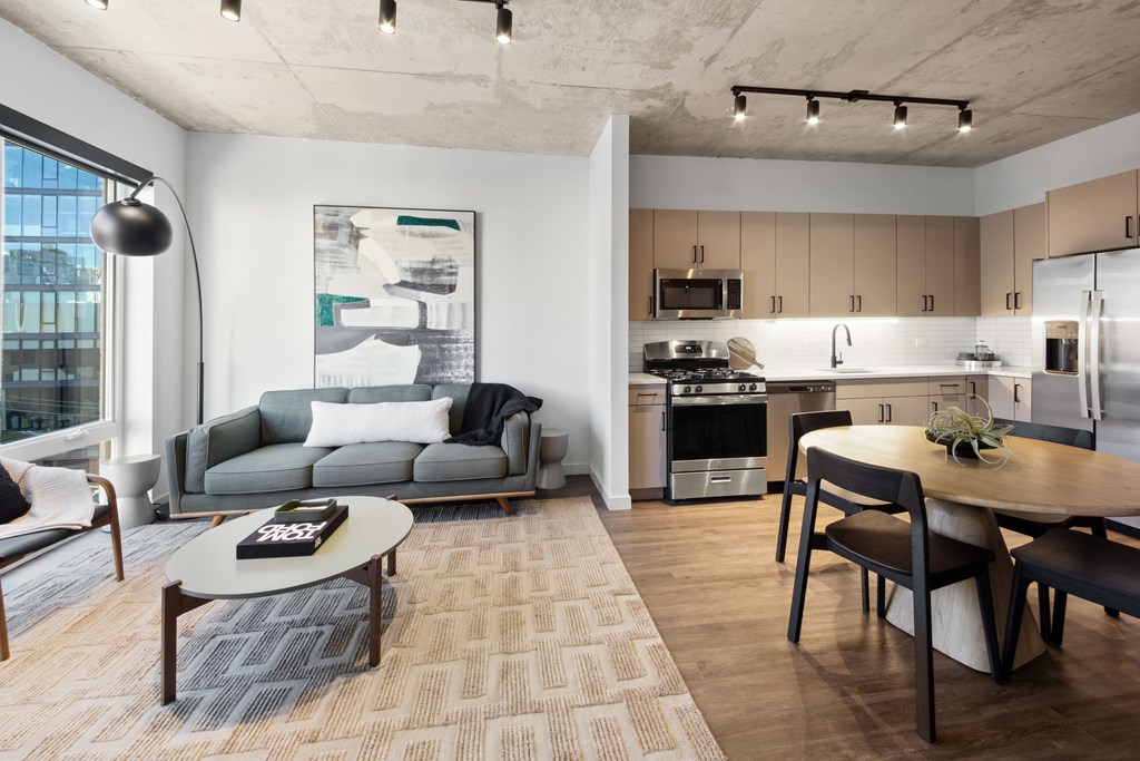 A modern kitchen and living room with a grey sofa and a coffee table.