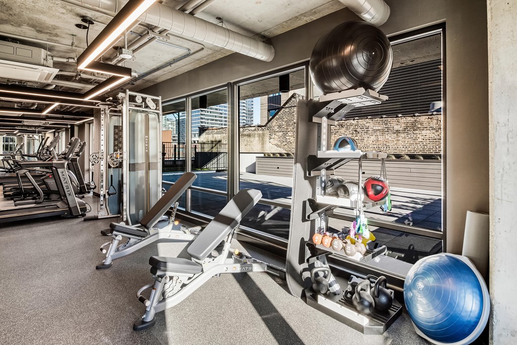 A gym with a variety of equipment including a treadmill, weights, and a medicine ball.