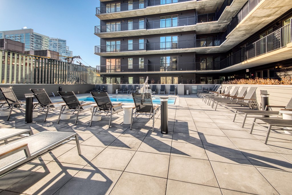 A sunny day at the rooftop pool with chairs and a table.