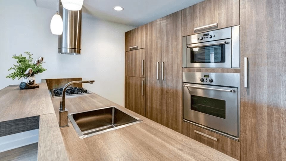 A modern kitchen with a wooden countertop and stainless steel appliances.