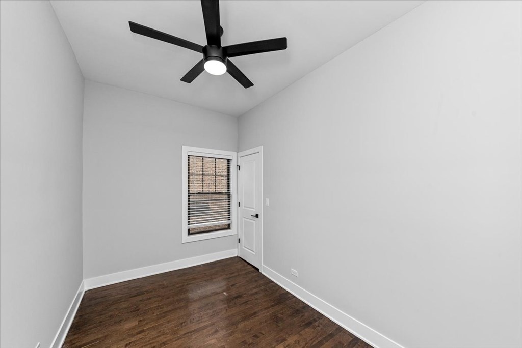 A room with a ceiling fan and a window with blinds.
