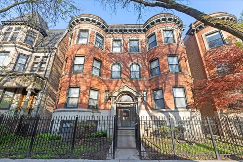 A large, red brick building with a black iron fence in front.
