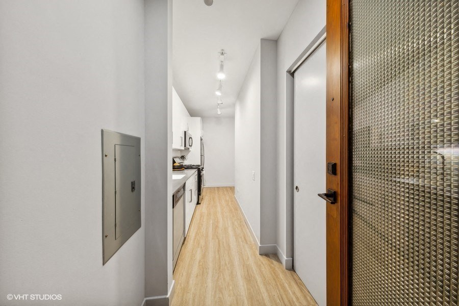 a long hallway with a door to a kitchen and a bathroom