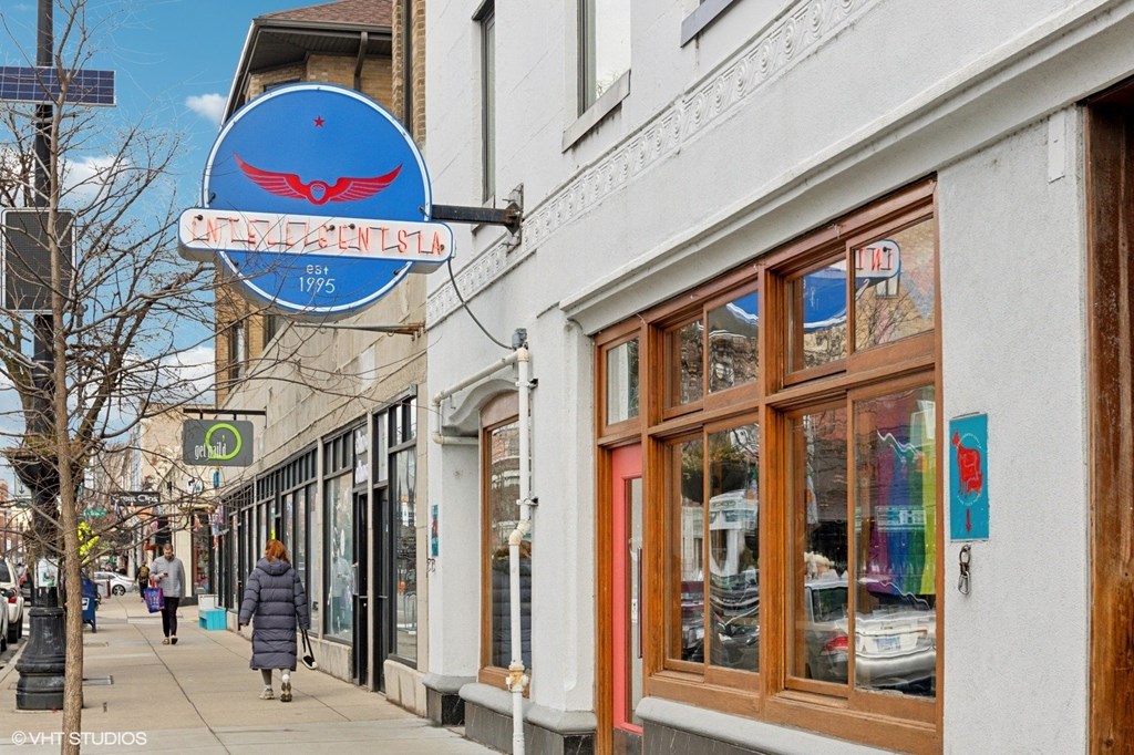 A blue sign with a bird on it hangs from a building.