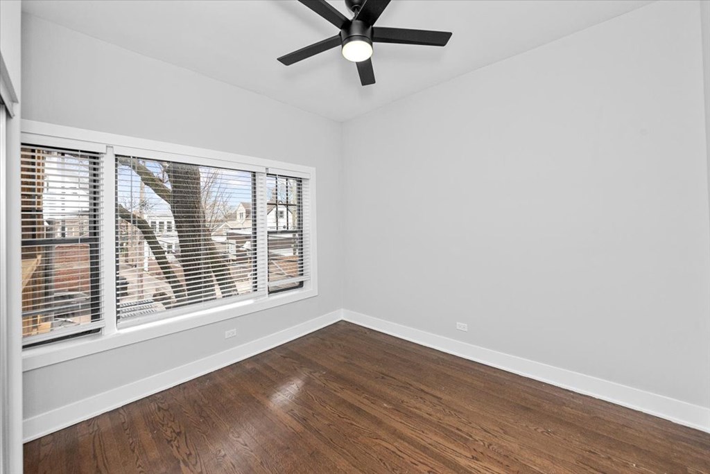 A room with a ceiling fan and a window with blinds.