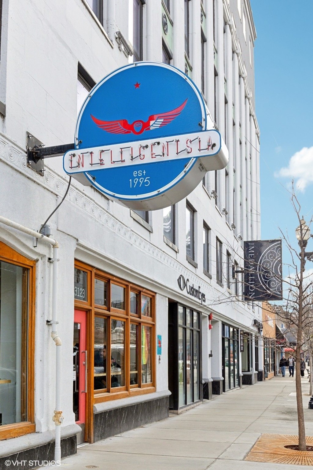 A blue sign with a red bird on it hangs from a building.