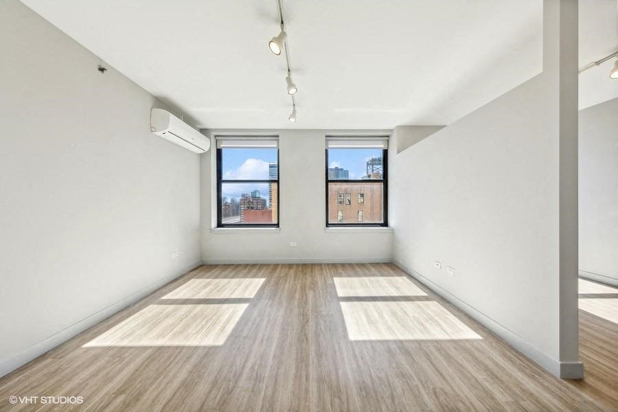 an empty living room with two windows and wood floors