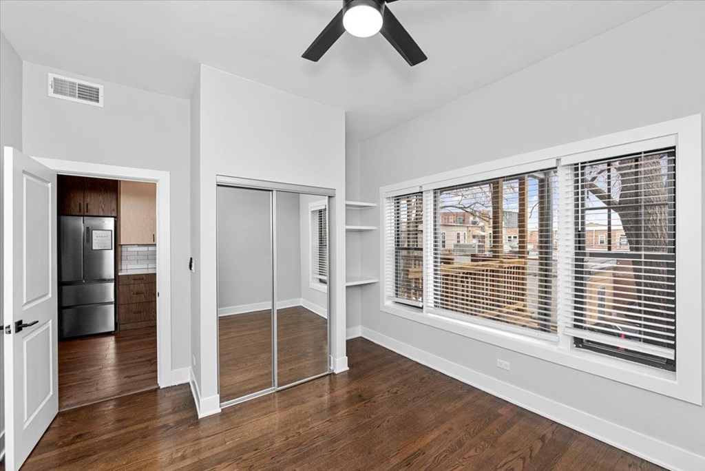 A room with a ceiling fan and sliding glass doors.