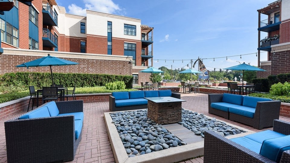 A patio with blue couches and a fire pit.