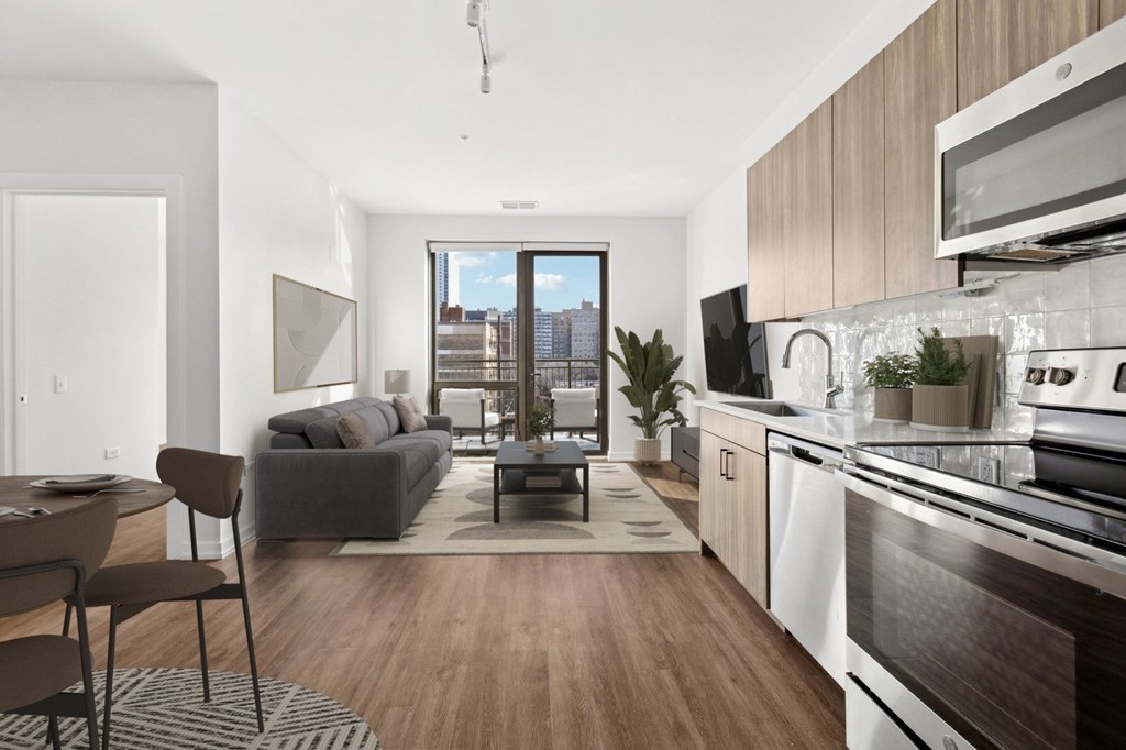 A modern kitchen with a dining table and chairs in the foreground and a living room with a couch and a coffee table in the background.