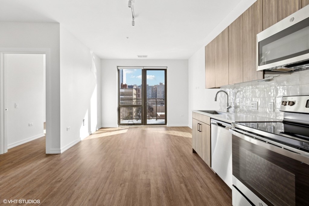A modern kitchen with wooden floors and stainless steel appliances.