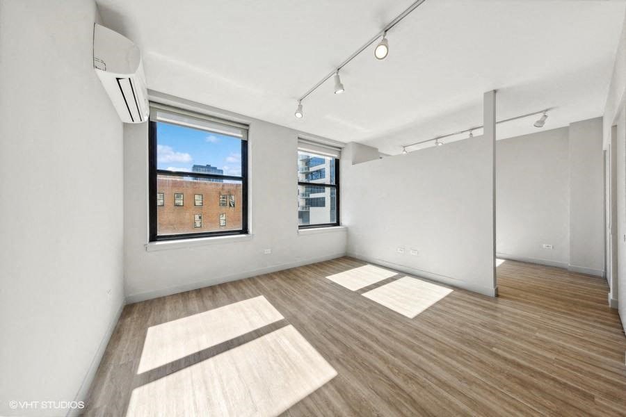 an empty living room with a window and wood floors