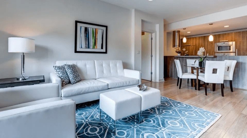 A modern living room with a white couch and a blue patterned rug.