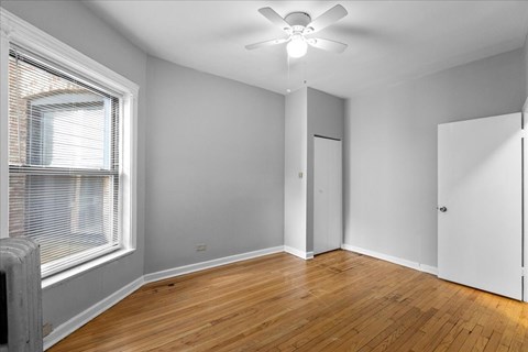A room with a ceiling fan and wooden flooring.