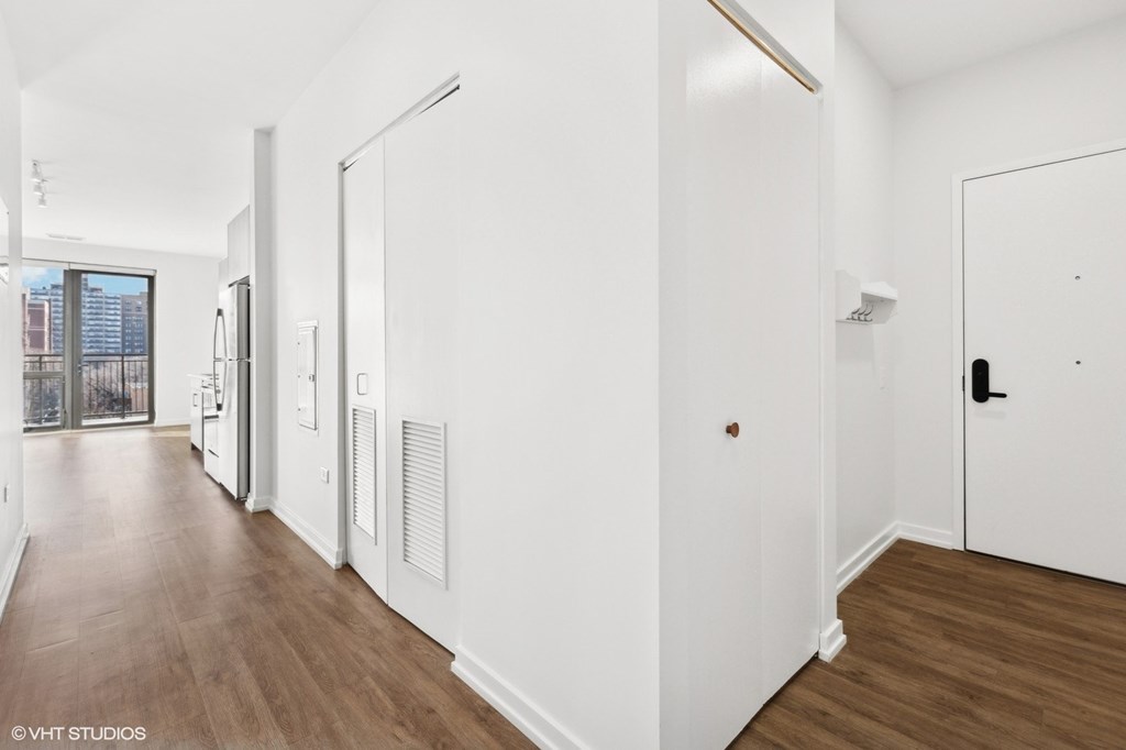 A long hallway with white walls and wood floors.