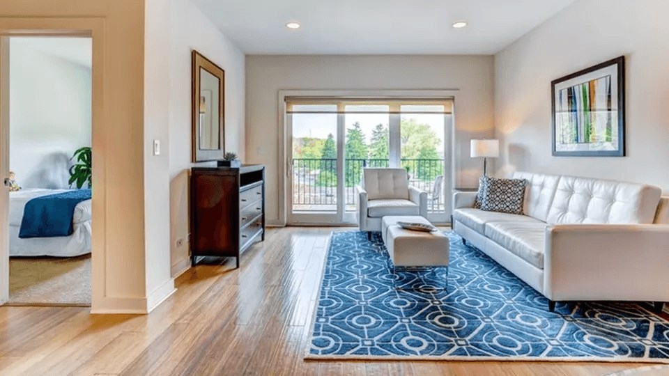 A living room with a white couch and a blue patterned rug.