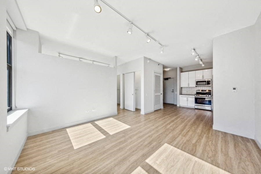 an empty living room and kitchen with white walls and wood floors