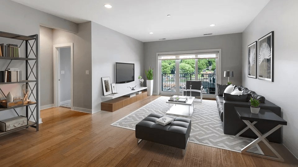 A modern living room with a black leather couch and a television.