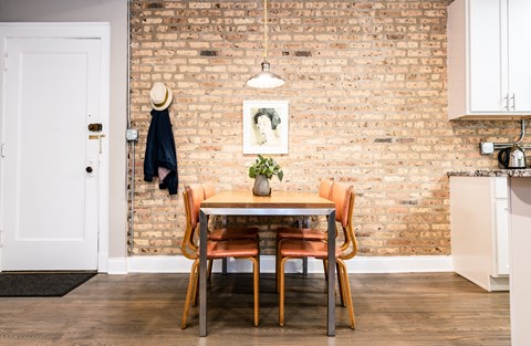 A dining room with a brick wall and a table with chairs.